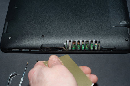 Hands of a computer repairman removing the back cover of the notebook.Computer repair shop. Engineer performing laptop maintenance. Hardware developer fixing electronic components. PC technologyの写真素材