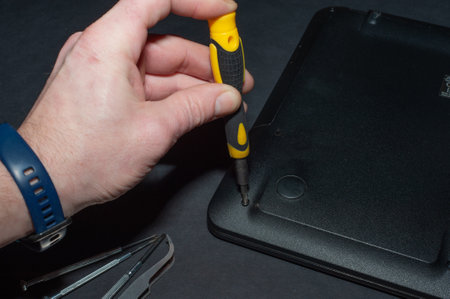 Hands of a computer repairman removing the back cover of the notebook.Computer repair shop. Engineer performing laptop maintenance. Hardware developer fixing electronic components. PC technologyの写真素材