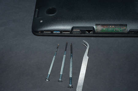 Hands of a computer repairman removing the back cover of the notebook.Computer repair shop. Engineer performing laptop maintenance. Hardware developer fixing electronic components. PC technologyの写真素材