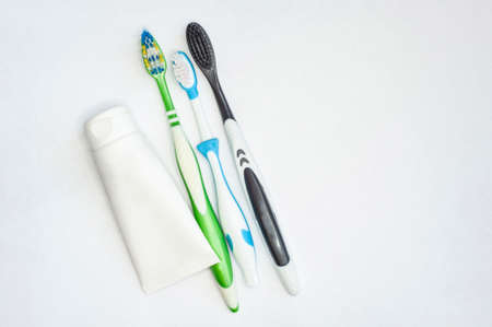 three toothbrushes for adults and children and a tube of paste on an isolated white background. with a place to insert textの写真素材