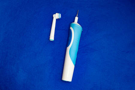 Modern electric toothbrush standing on a blue background. Controlled tool for daily oral care.の写真素材