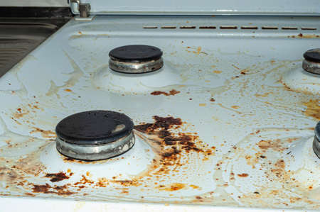 Dirty stove with food leftovers. Unclean gas kitchen cooktop with greasy spots, old fat stains, fry spots and oil splatters.の写真素材