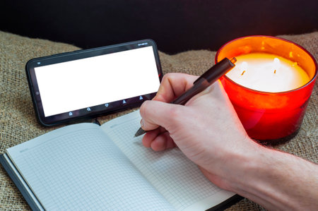 A phone with a clean, free space, a notebook and candles in a red glass, ideas for recreation, planning, prospectsの写真素材