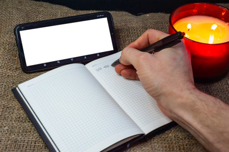 A phone with a clean, free space, a notebook and candles in a red glass, ideas for recreation, planning, prospectsの写真素材