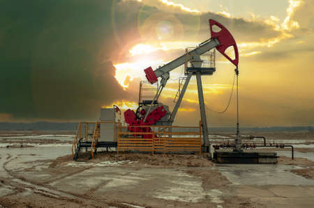 Crude oil pump jack at oilfield on sunset backround. Fossil crude output and fuels oil production. Oil drill rig and drilling derrick. Global crude oil Prices, energy, petroleum demand.の写真素材