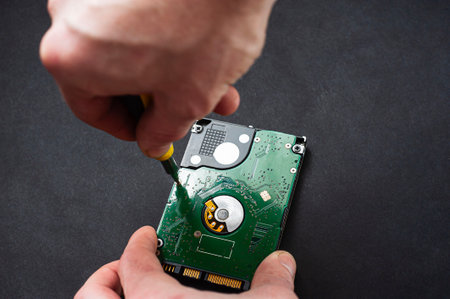 Engineer fixing broken computer hard disc. Electronic repair shop, technology development concept.の写真素材