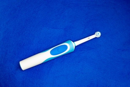 Modern electric toothbrush standing on a blue background. Controlled tool for daily oral care.の写真素材