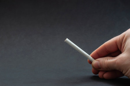 Man holding broken cigarette in hand. Stop smoking. Cigarette, nicotine damage, lungs ruined by smoke. World No Tobacco Day.の写真素材