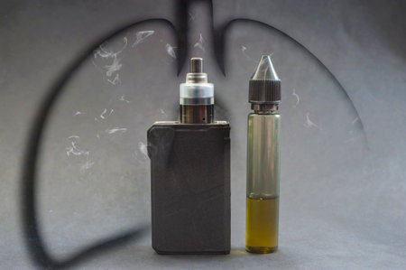 electronic cigarette on a dark background with a silhouette of lungs filled with steam or smoke.の写真素材