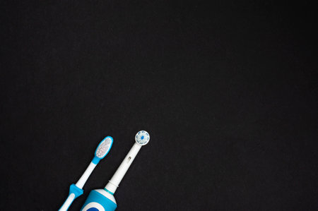 Modern electric toothbrush standing on a black background. Controlled tool for daily oral care.の写真素材