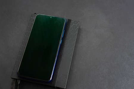 notepad and mobile phone on a black background, table. Financial calculations, black shades.の写真素材