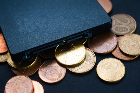 A bunch of coins, on a black background, and a solid-state drive, the growth, the fall in the price of memory.の写真素材