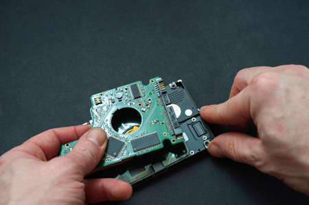 Engineer fixing broken computer hard disc. Electronic repair shop, technology development concept.の写真素材