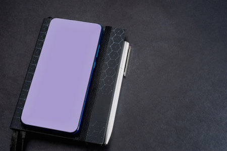 notepad and mobile phone on a black background, table. Financial calculations, black shades.の写真素材