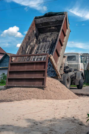 Dump trucks carrying good filling a field, giving rise to a fine soil. Preparation and construction.の写真素材