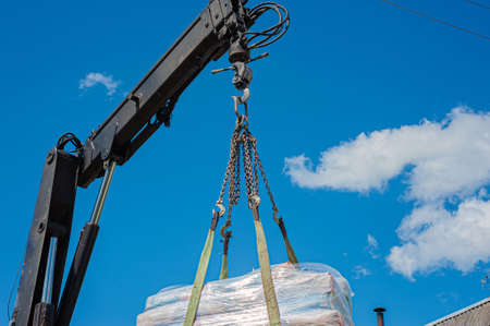 Unloading paving slabs from a truck. Men unload paving slabs using a manipulator.の写真素材
