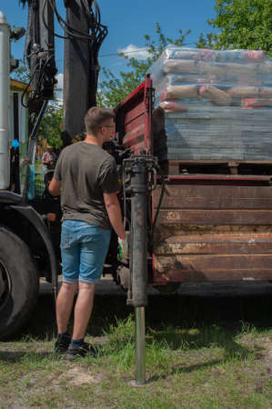 Unloading paving slabs from a truck. Men unload paving slabs using a manipulator.の写真素材
