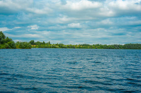 River bay, forest on the shore. A beautiful bay overgrown along the shore with a green forest under a deep blue skyの写真素材