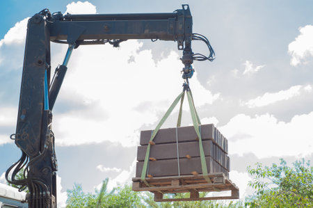 Unloading paving slabs from a truck. Men unload paving slabs using a manipulator.の写真素材
