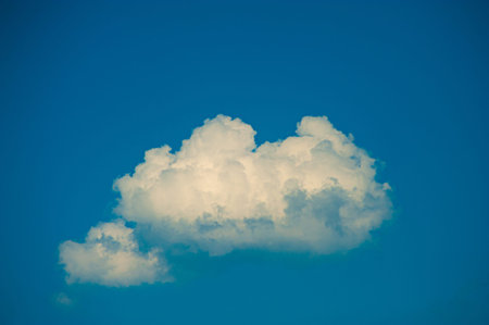 Puffy white cloud on clear blue sky.