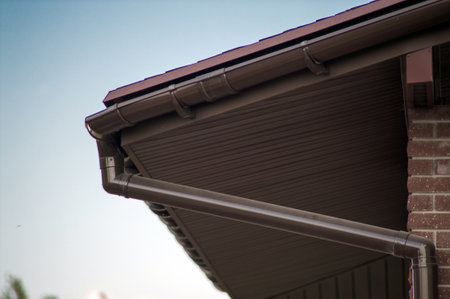 Corner of the house with new gray metal tile roof and rain gutter. Metallic Guttering System, Guttering and Drainageの写真素材