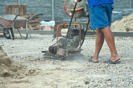 Vibratory plate construction site. Construction workers installing and arranging precast concrete pavers stone for road at the construction siteの写真素材