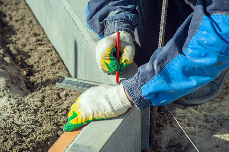 A worker measures a concrete block with a ruler, close-upの写真素材