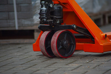 Old orange manual hand pallet trucks. Close up wheel of hydraulic hand pallet truck.の写真素材