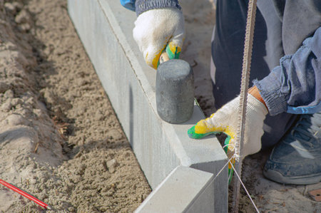 Workers using machine to align and set the concrete curbs. Concrete kerb installation at sidewalk edgingの写真素材