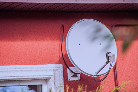 Satellite TV antenna on the wall of the house on a summer dayの写真素材