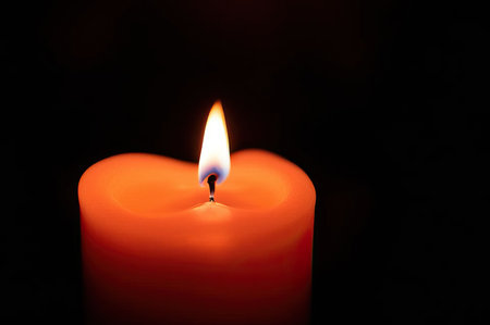 Close-up of a woman's hands lighting a candle with a match in the dark.の素材