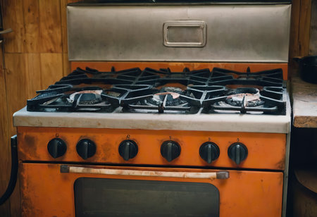 The gas burner on the dirty stove is on. Fire from a gas burner. blue flame from the stove gas comcorder. Dirty stove.の素材