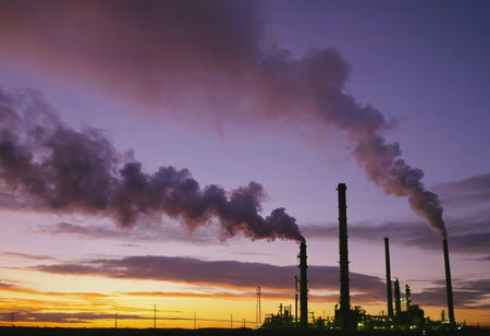Smoke from heating station in big city during winter season at sunset. Smokestack pipes emitting co2 from coal thermal power plant into atmosphere. Air pollution and emission ecology problem conceptの素材