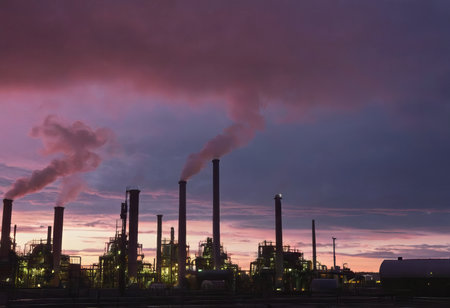 Smoke from heating station in big city during winter season at sunset. Smokestack pipes emitting co2 from coal thermal power plant into atmosphere. Air pollution and emission ecology problem conceptの素材