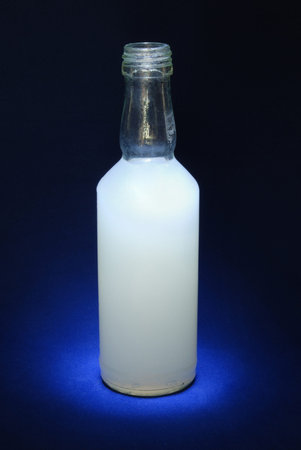 A bottle with a white drink on a blue backgroundの写真素材