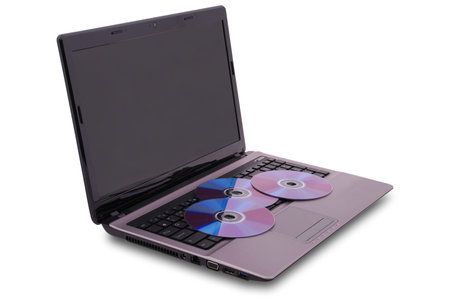 Laptop on white background. Three CD are on the keyboard