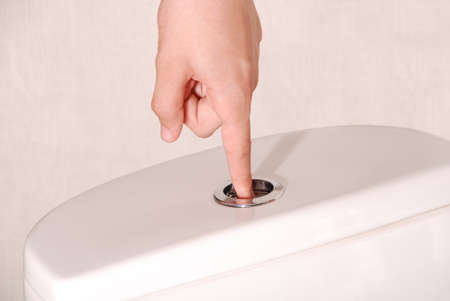 Children hand flushing toilet. Space available on left-hand and right-hand side for text.の写真素材