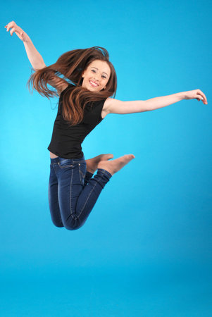 Girl jumping isolated on blue studio background.