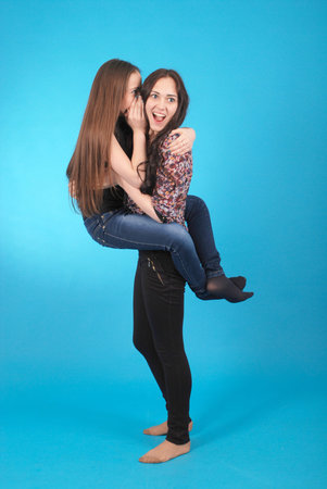 One young girl tells the other important news on blue studio .の写真素材