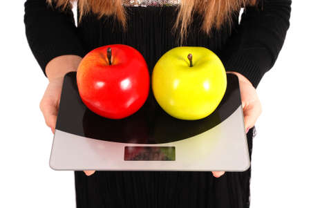 girl measures the weight of apples isolated on whiteの写真素材