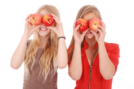 Two girls hold near eyes fresh apples isolated on whiteの写真素材