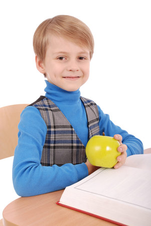 Boy sitting at a school desk isolated on white