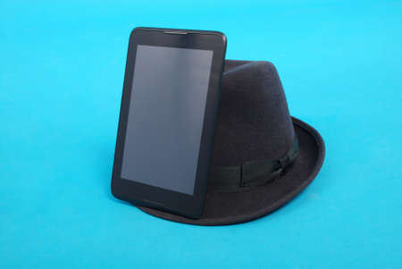 Tablet PC is at the felt hat isolated on blue backgroundの写真素材