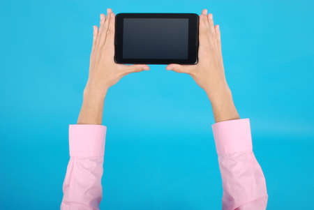 Male hand holding a touchscreen isolated on blue backgroundの写真素材