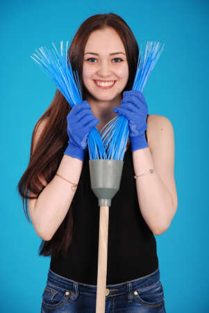 Girl playing with a broom isolated on blueの写真素材