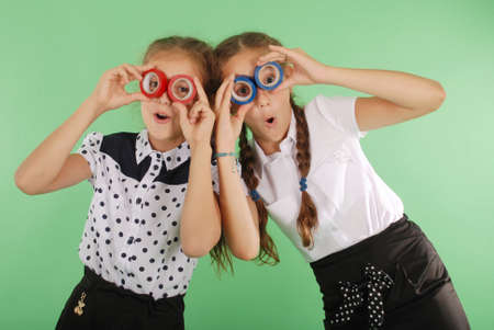 Two beautiful school girl holding two insulating tape on eyes for radiant look on greenの写真素材