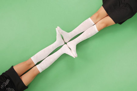 Two girls in knee-length socks isolated on green backgroundの写真素材