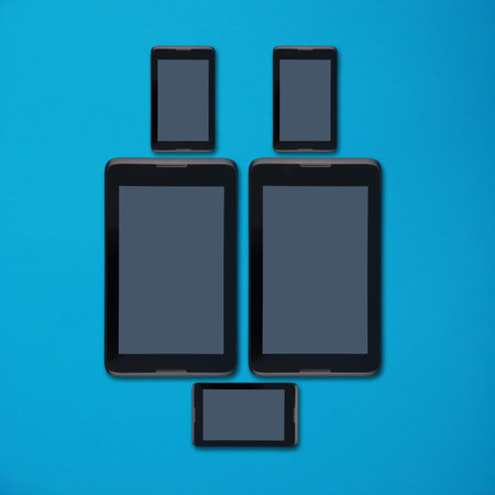 Tablet pc and smartphone lying side by side isolated on blue background with soft shadow