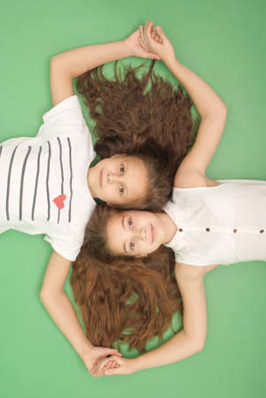Portrait of two young girls with long hair, top view, isolated on greenの写真素材