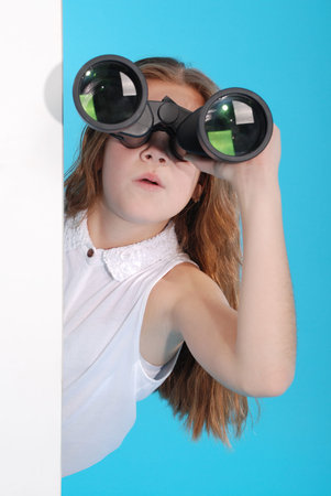 Young girl with binoculars isolated on blue backgroundの写真素材
